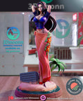 Sculptor's render of the painted design (kit ships unpainted): front view of the dark-haired woman with her hands behind her head, in a blue zip jacket and coral sarong, on the round beach base with a carved stone block and a small palm