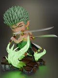 Sculptor's render of the painted design (kit ships unpainted): three-quarter view of the green-haired chibi swordsman crouched with a sword in his teeth and one in each hand, ringed by green energy effects on the broken stone base