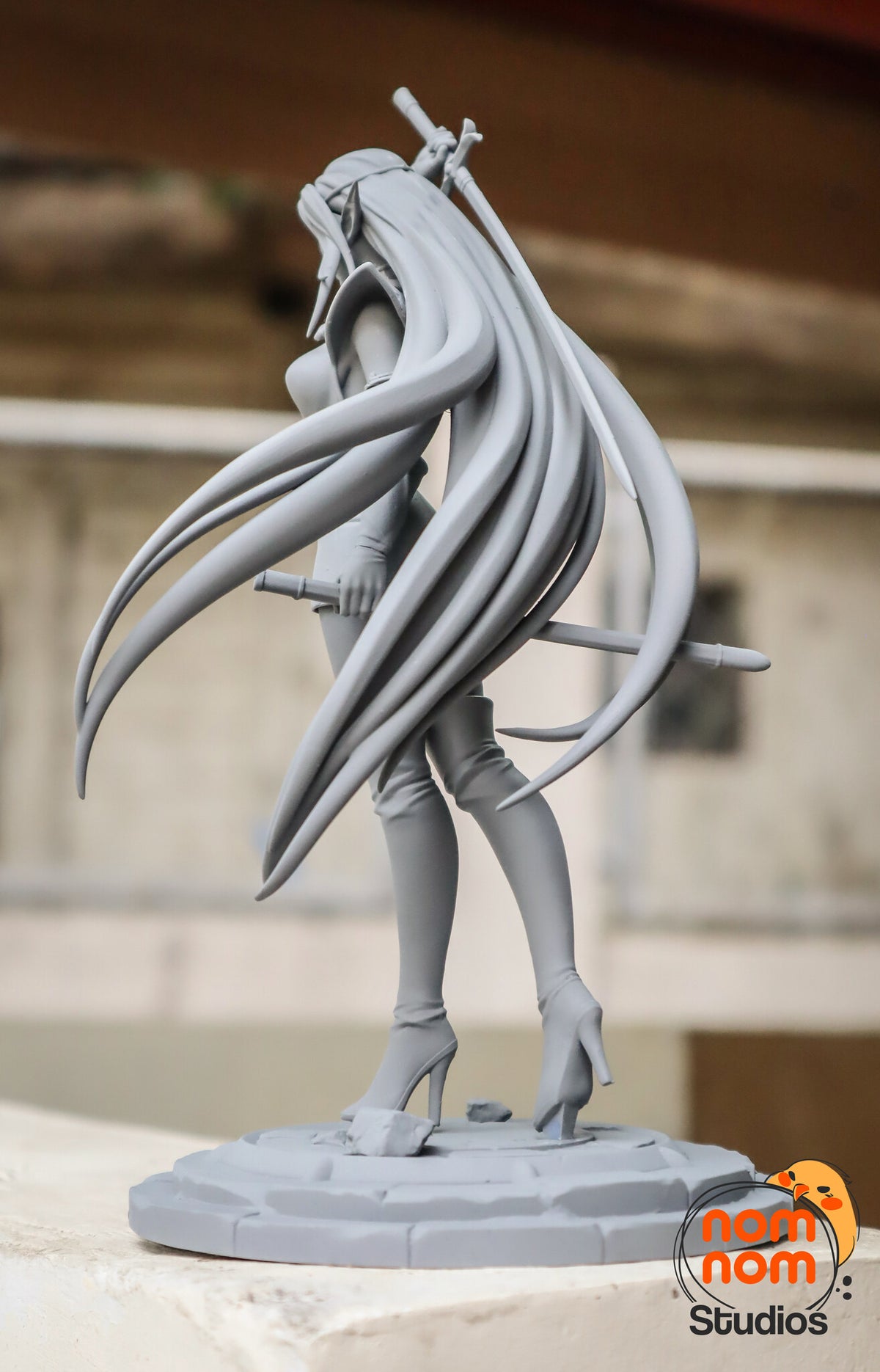 Sculptor's photo of an unpainted print: rear three-quarter view showing the level sword behind her legs and the spread of hair strands