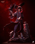 Sculptor's render of the painted design (kit ships unpainted): full front view of the black-haired ninja in a black cloak with red clouds, crows lifting off his raised hand, on a rock base with a tall pillar