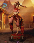 Sculptor's render of the painted design (kit ships unpainted): front three-quarter full view of the acrobat balanced on one leg, one arm over her head and her braid swinging out, between three red pennants on the round stage base
