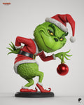 Sculptor's render of the painted design (kit ships unpainted): three-quarter front view of the chibi green grump in a red Santa suit, leaning forward on the round black base and dangling a red bauble