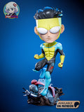 Sculptor's render of the painted design (kit ships unpainted): front view of the yellow-cowled superhero stepping off a rubble pile, one knee raised and both fists clenched, robot wreckage and a pink alien brain in the rocks