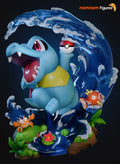 Sculptor's render of the painted design (kit ships unpainted): the light blue chibi crocodile leaping off a curling blue wave with a red and white ball held overhead, a small crab on the rocks at left and a fish on the foam at right