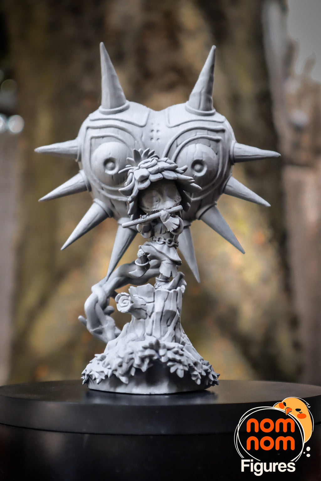 Sculptor's photo of an unpainted print: front view on a turntable, the spiked mask filling the top of the frame above the imp and the stump