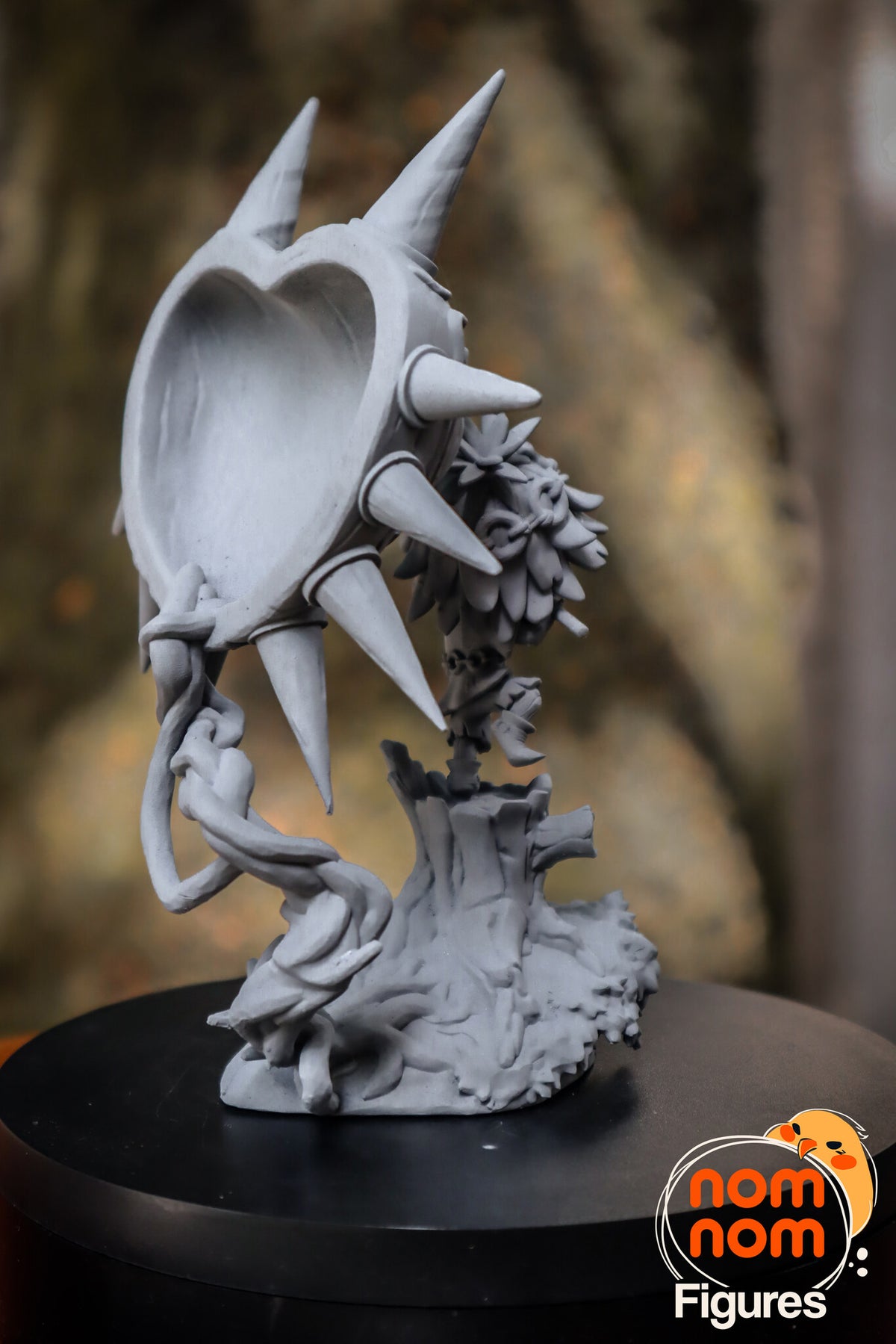 Sculptor's photo of an unpainted print: rear three-quarter view of the hollow heart-shaped back of the mask held up by the vine