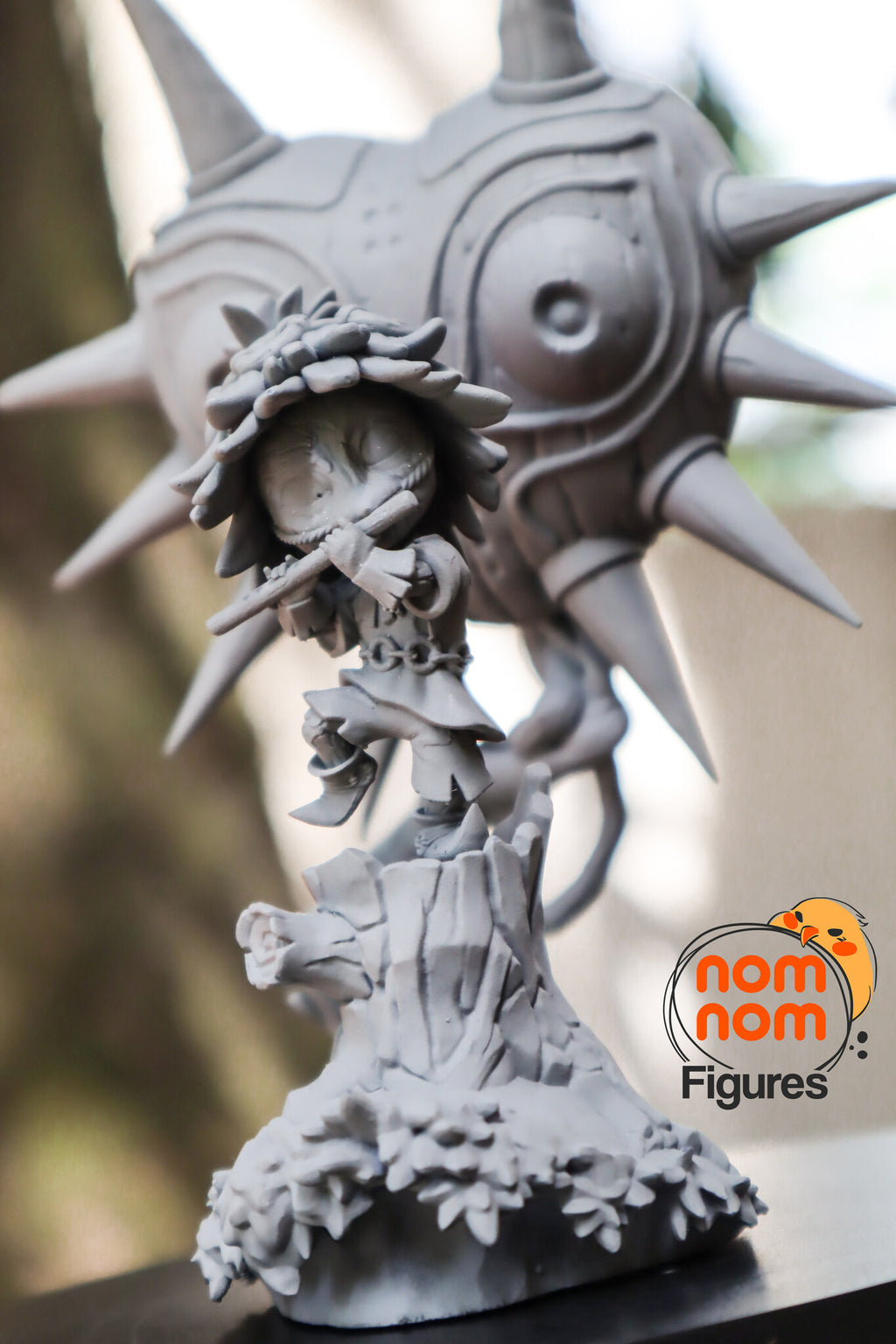 Sculptor's photo of an unpainted print: low front view of the imp on the carved stump with the spiral-cut branch, the mask behind