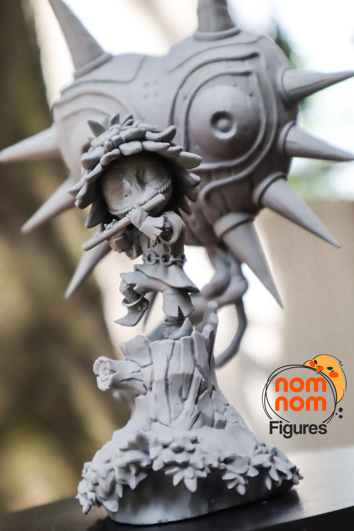 Sculptor's photo of an unpainted print: low front view of the imp on the carved stump with the spiral-cut branch, the mask behind